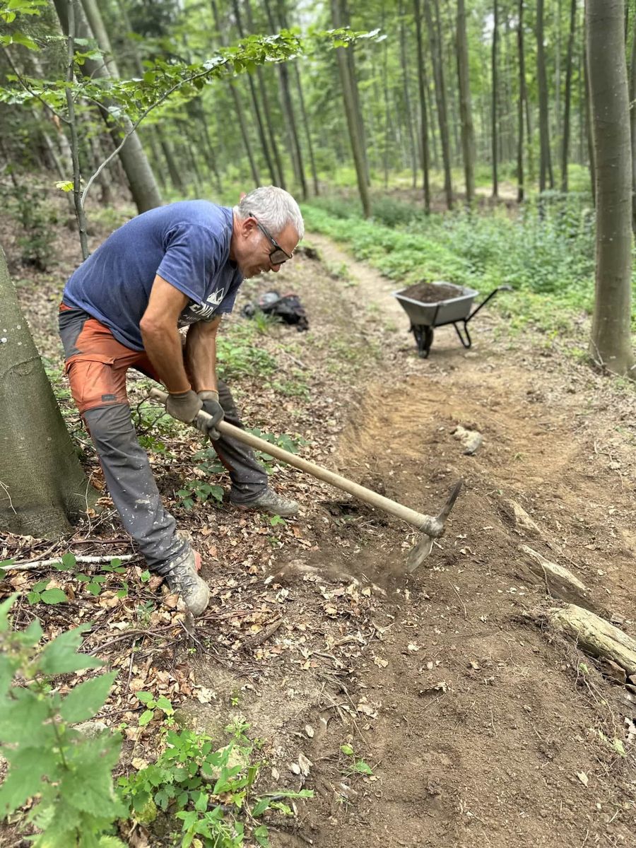 Trailbauer schaufelt einen Singletrail im Wald